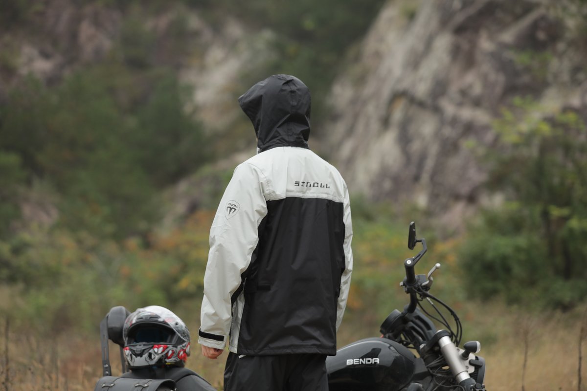 Rider in MOTOSINOLL rainwear beside a motorcycle